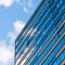 blue sky and clouds reflecting in the glass of an office building